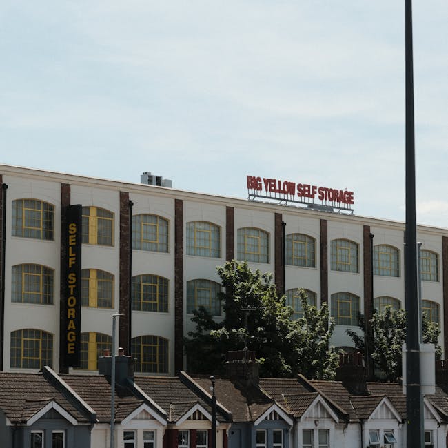 A daytime street scene shows multi-storey residential and commercial buildings with brick and ornate architectural details, situated on a city road in Finsbury Park. A small delivery van, branded with